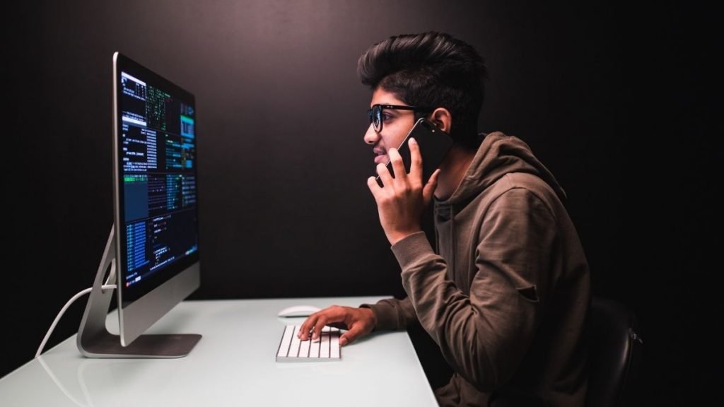 A Person Talking On Phone And Using Laptop
